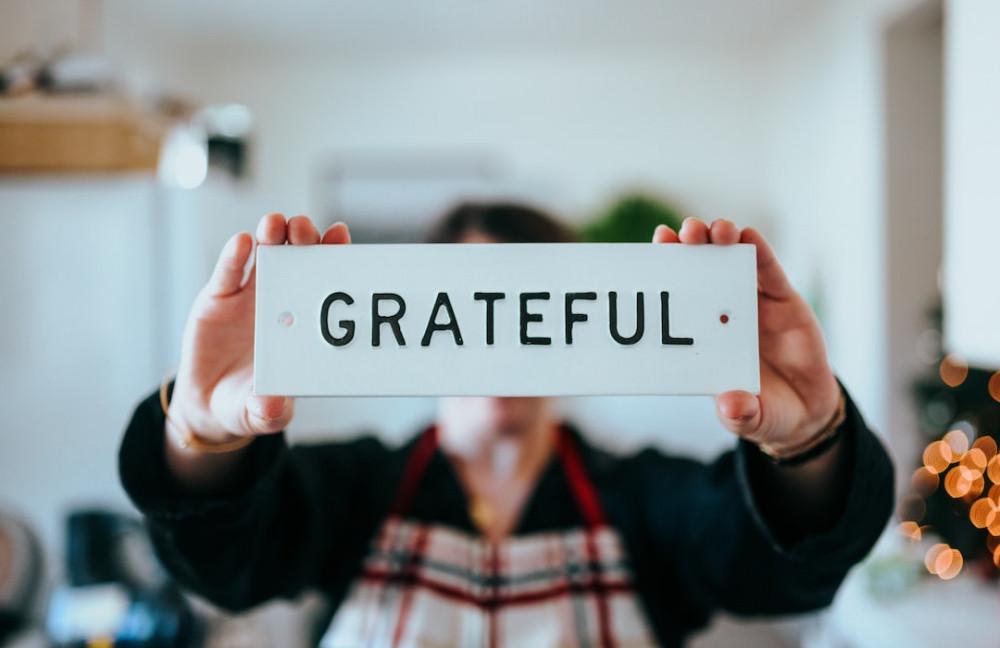 Person holding up sign saying grateful to show of being grateful of many things in life.